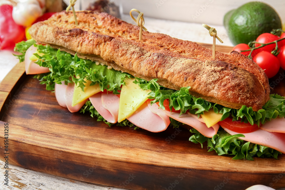 Board with tasty ciabatta sandwich on light wooden background, closeup