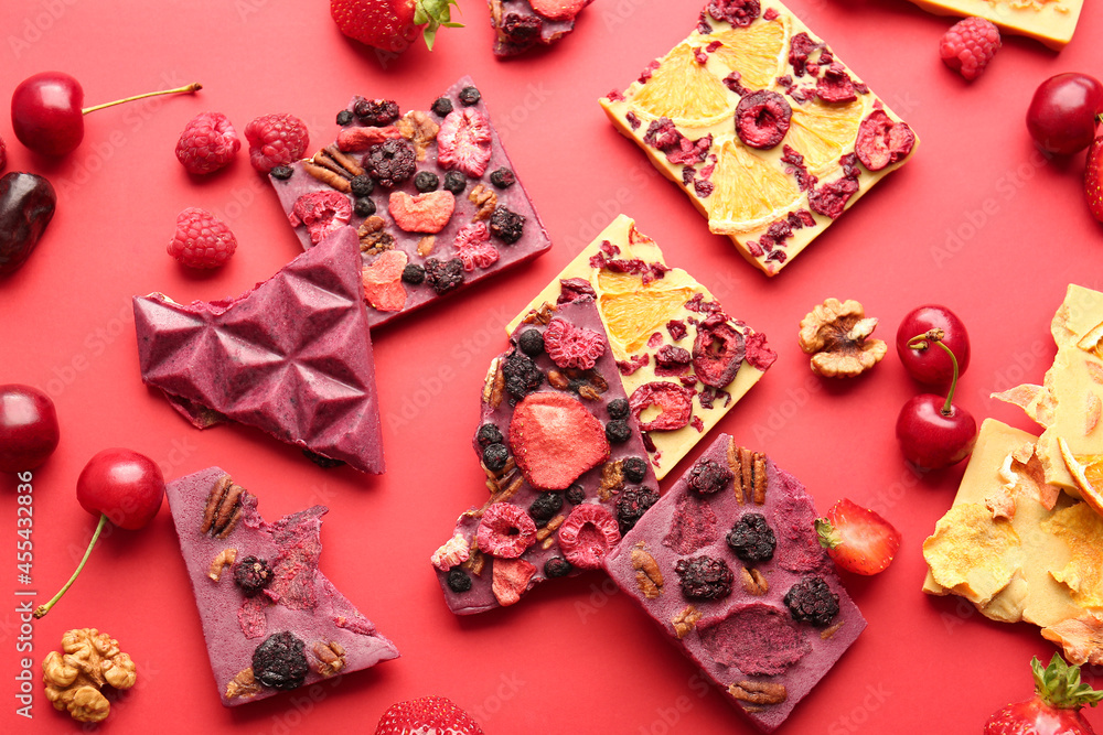 Handmade chocolate bars with fruits and berries on color background