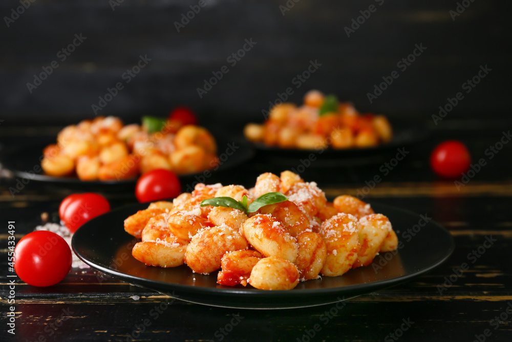 Delicious gnocchi with tomato sauce in plate on dark wooden table