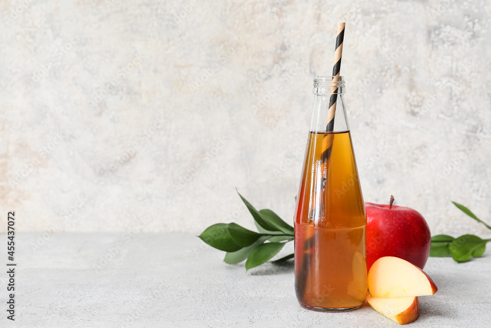 Bottle of apple juice and fresh fruits on light background