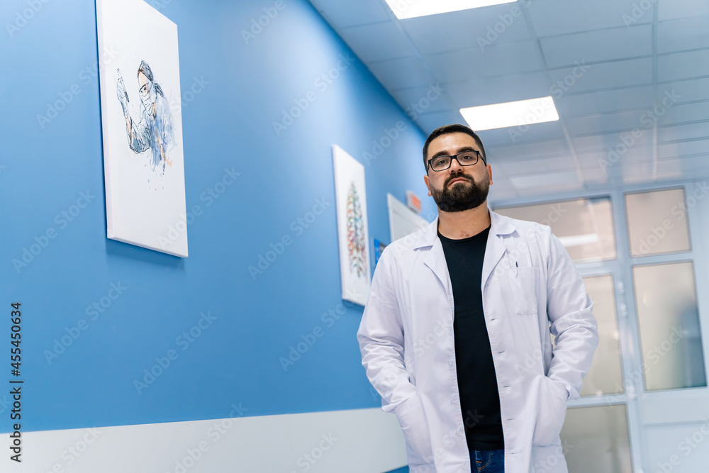 Professional medical specialist standing in modern hospital. Confident handsome doctor in uniform lo