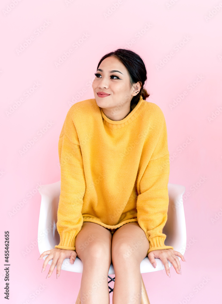 Asian woman sitting on white chair with pink background