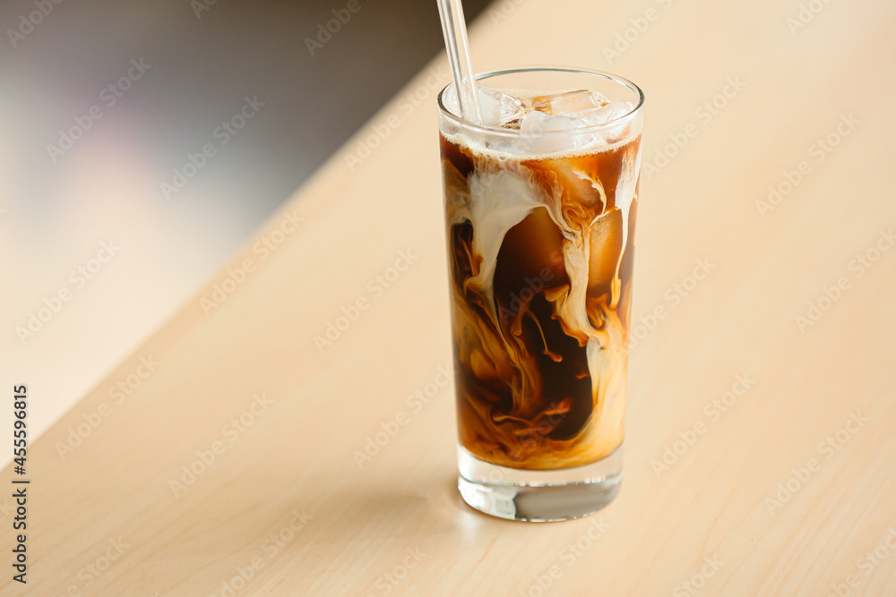 Glass of tasty ice coffee on table