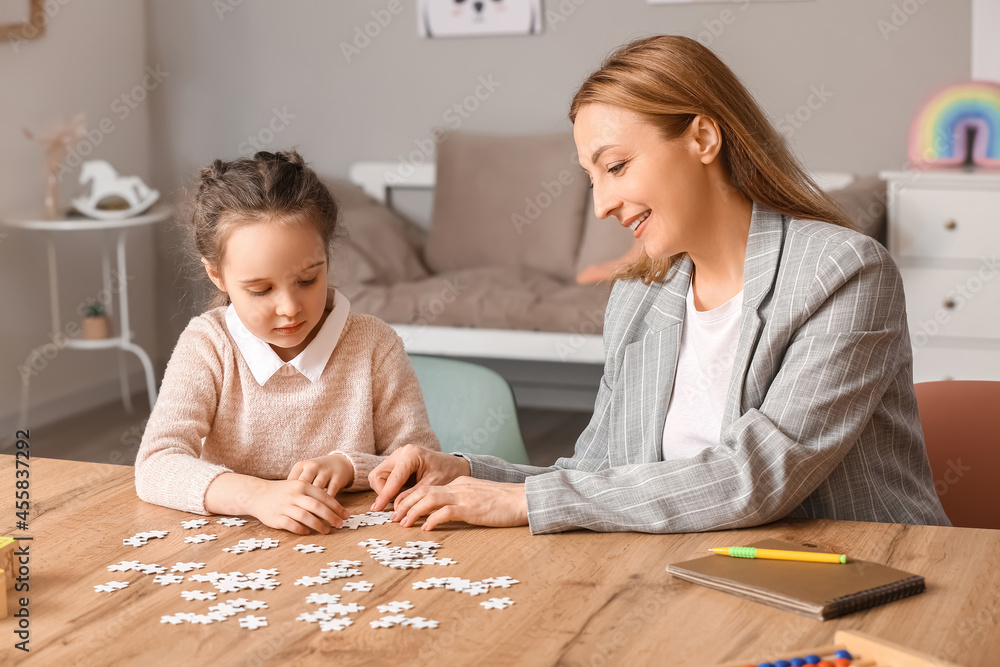 Female psychologist working with girl suffering from autistic disorder in office