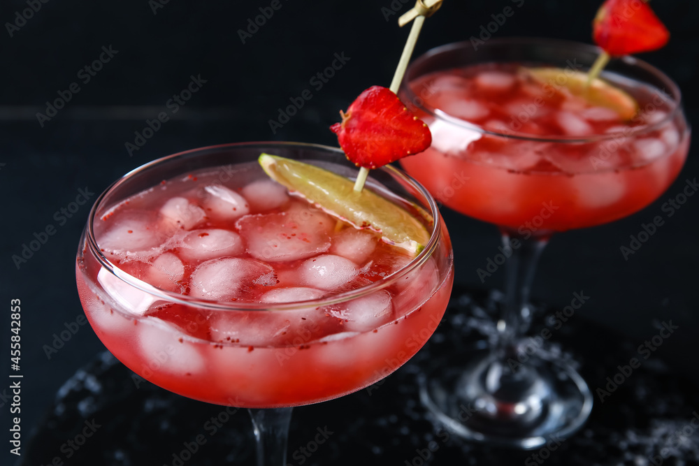 Glasses of tasty strawberry margarita on dark background, closeup