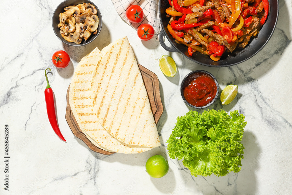 Tortillas and ingredients for tasty Fajitas on light background