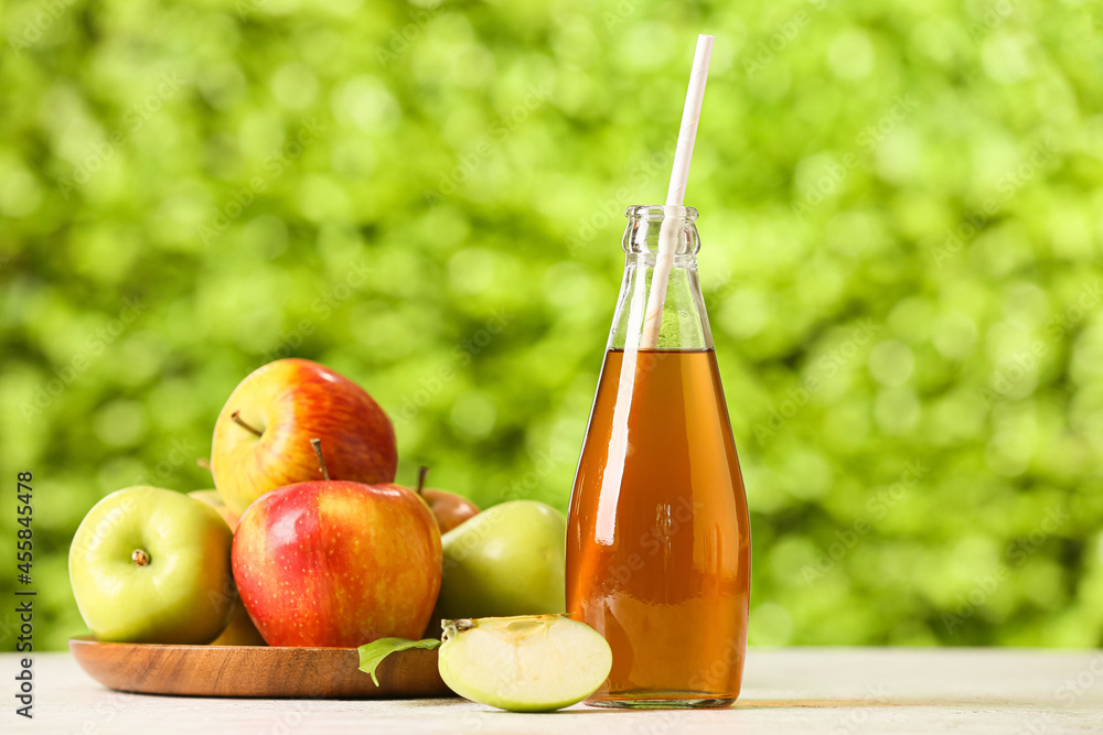 Bottle of apple juice and fresh fruits on table outdoors