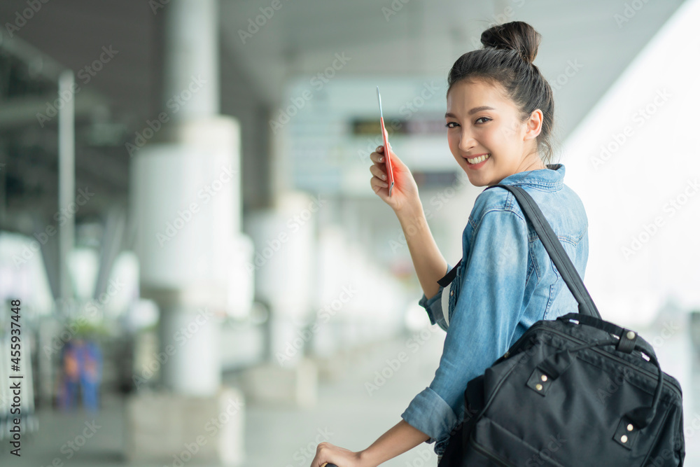 魅力四射的亚洲女性，穿着休闲旅行服，在等待过境出发大楼