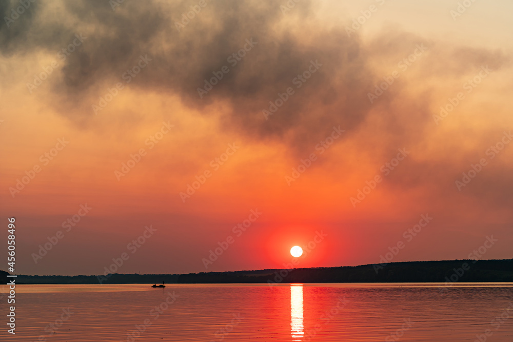 美丽的日落在大湖或大海之上。日落海滩。橙色的天空。在深水中划船