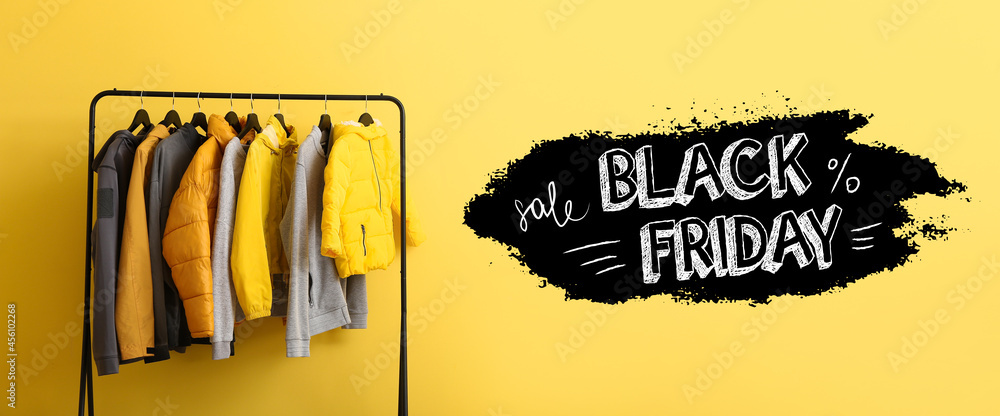 Rack with stylish clothes and text BLACK FRIDAY SALE on color background