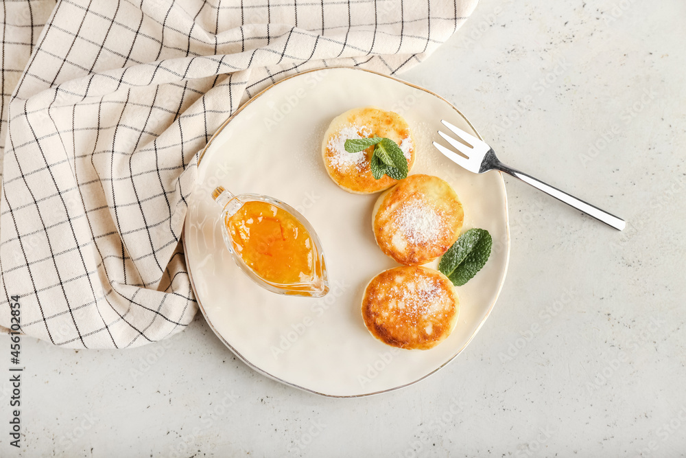 Plate with tasty cottage cheese pancakes and jam on light background