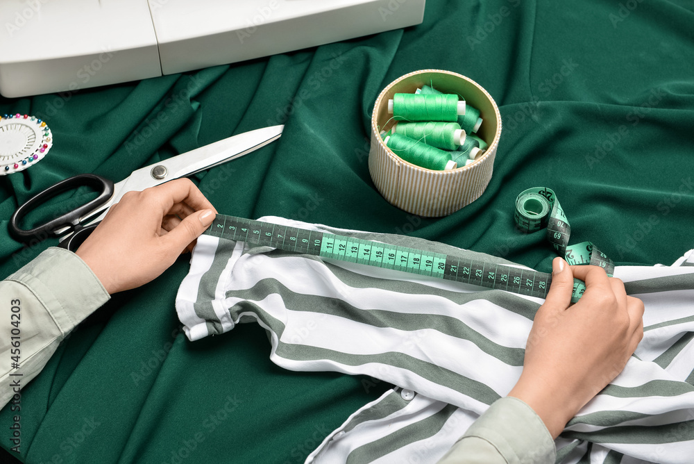 Woman measuring clothes on fabric background