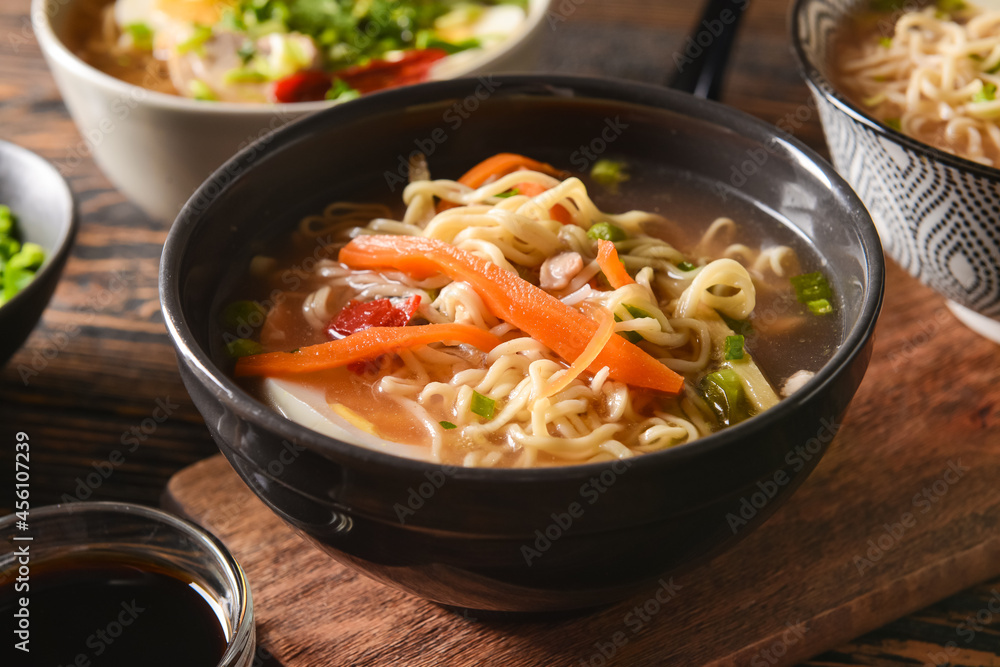 Tasty Chinese soup in bowl on wooden background, closeup