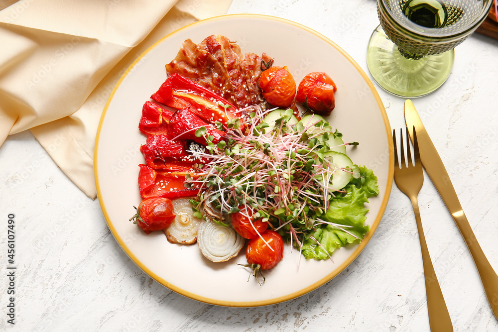 Plate of tasty salad with vegetables, fried bacon and micro green on light background