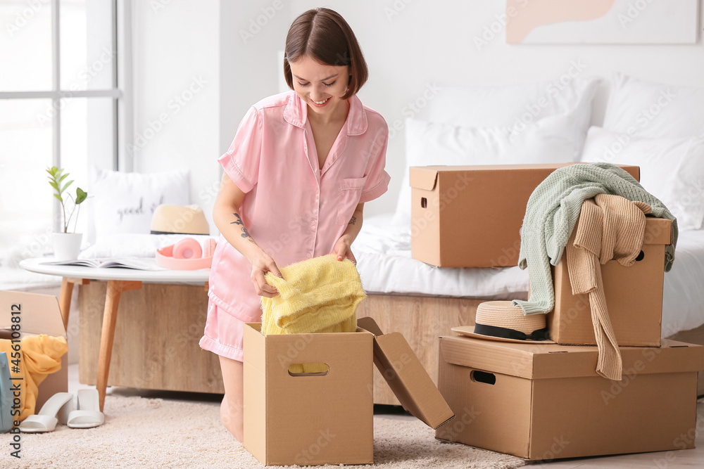 Young woman organizing clothes in bedroom