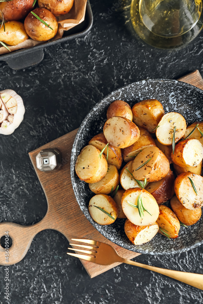 Plate with baked potatoes and rosemary on dark background