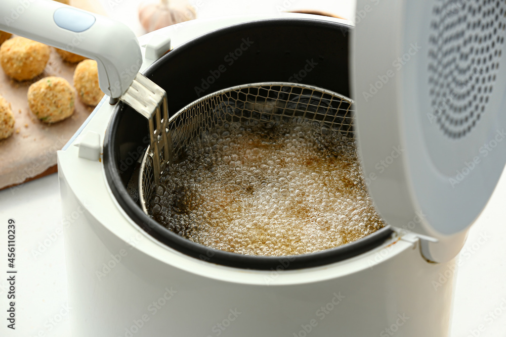 Cod cutlets preparing in deep fryer on table, closeup