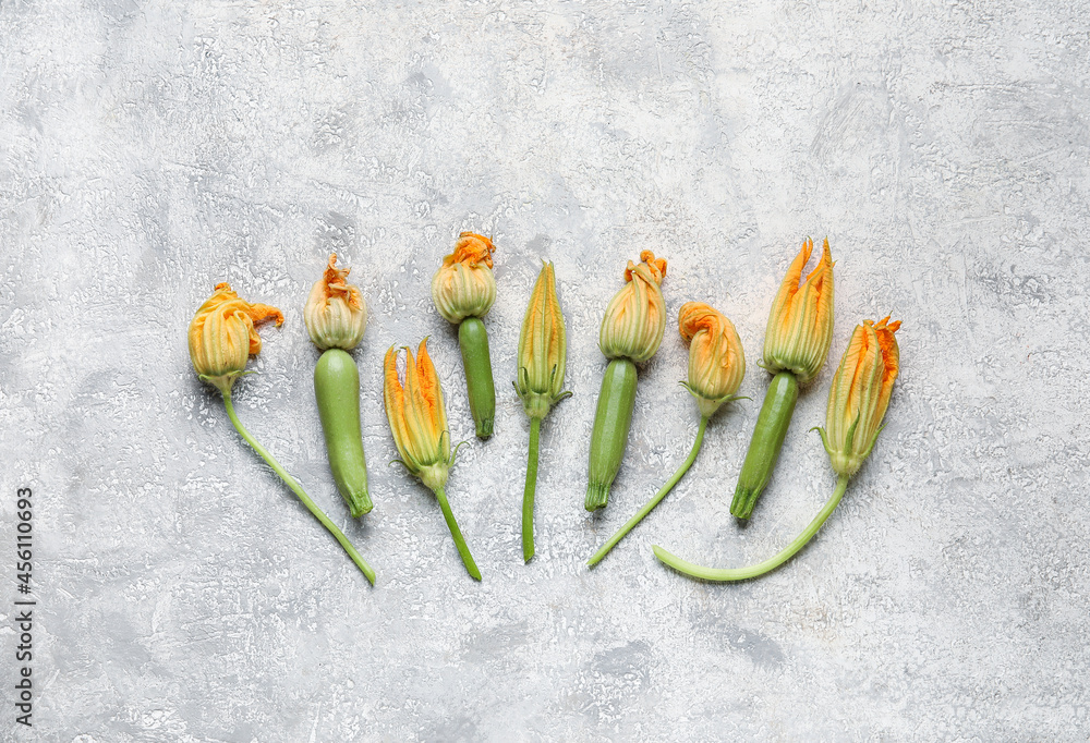 Fresh zucchini with flowers on grey background