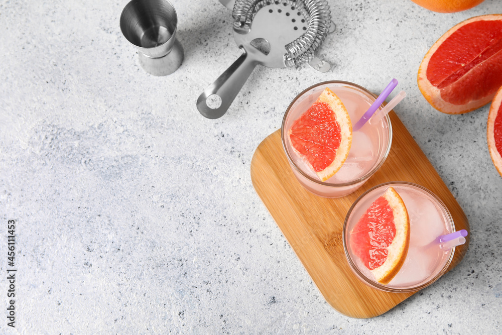 Glasses of tasty grapefruit margarita on light background