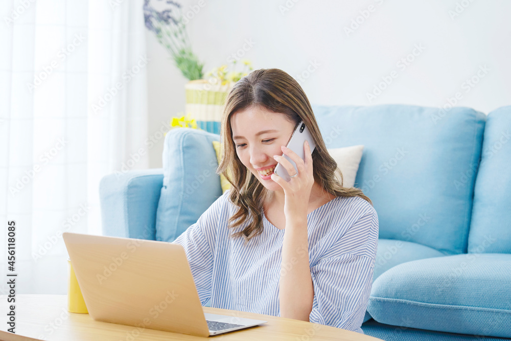 部屋でスマホで話す女性