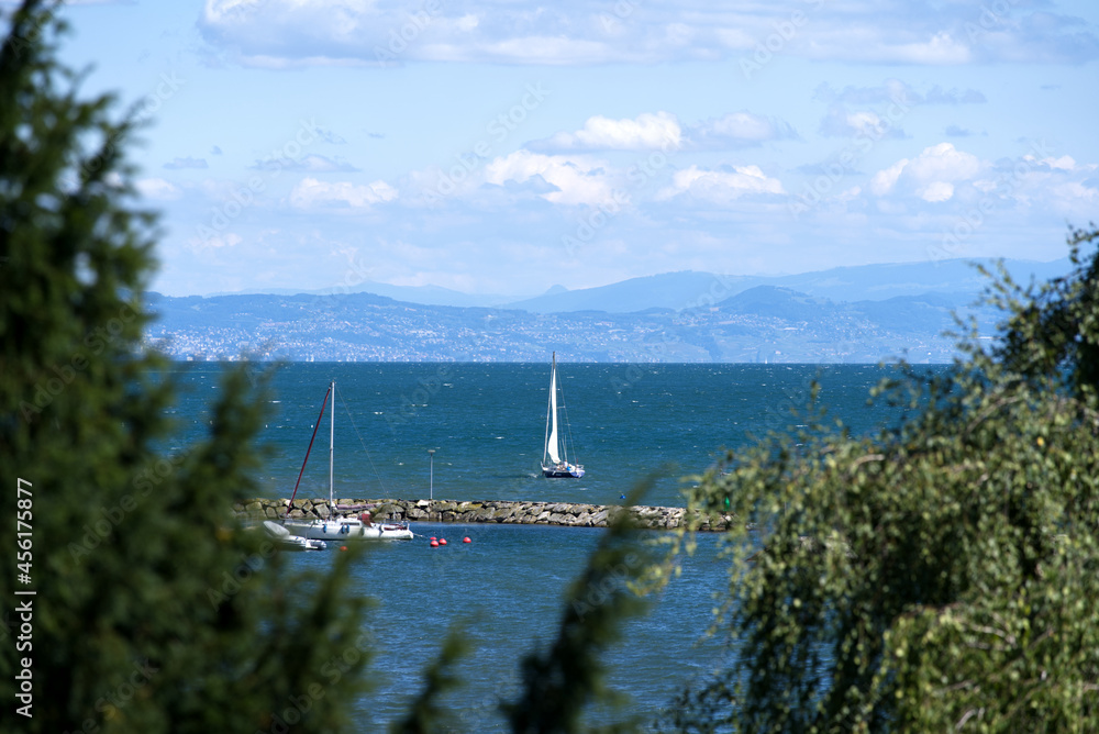 阳光明媚、风大的夏日日内瓦湖，背景是帆船和欧洲阿尔卑斯山。P