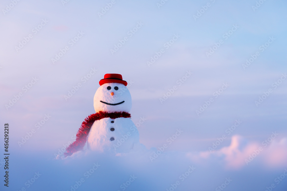 日落时，雪地上戴着时髦的红色帽子和红色鳞片的有趣雪人。圣诞快乐，哈哈