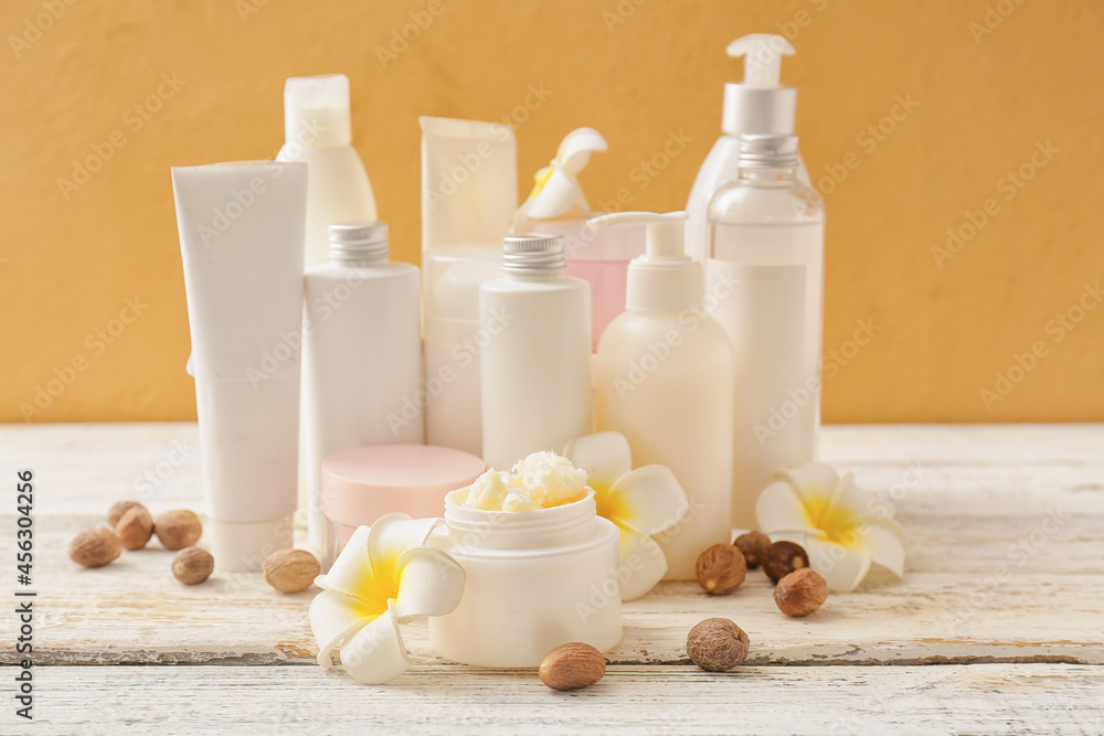 Jar of shea butter and different cosmetic products on wooden table