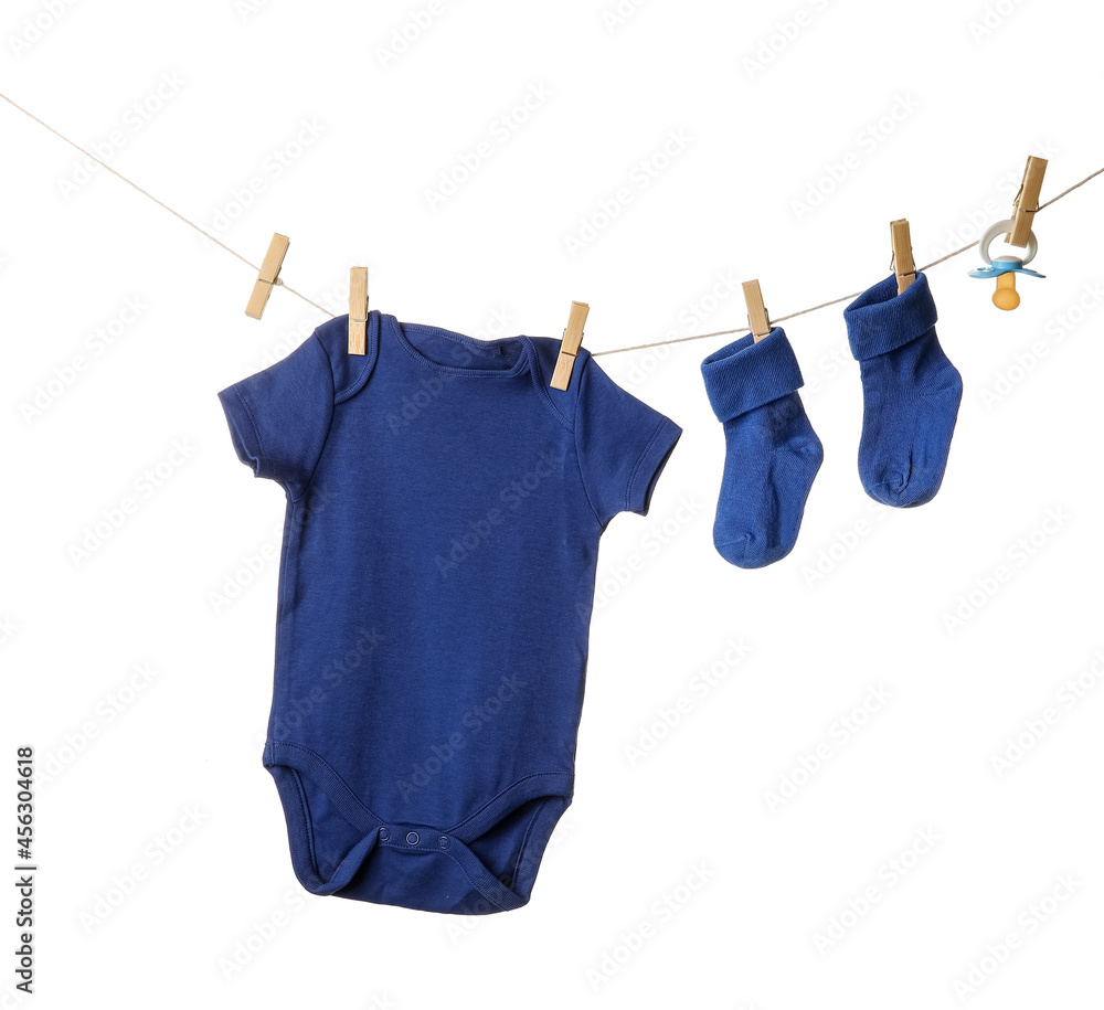 Baby clothes and pacifier hanging on rope against white background