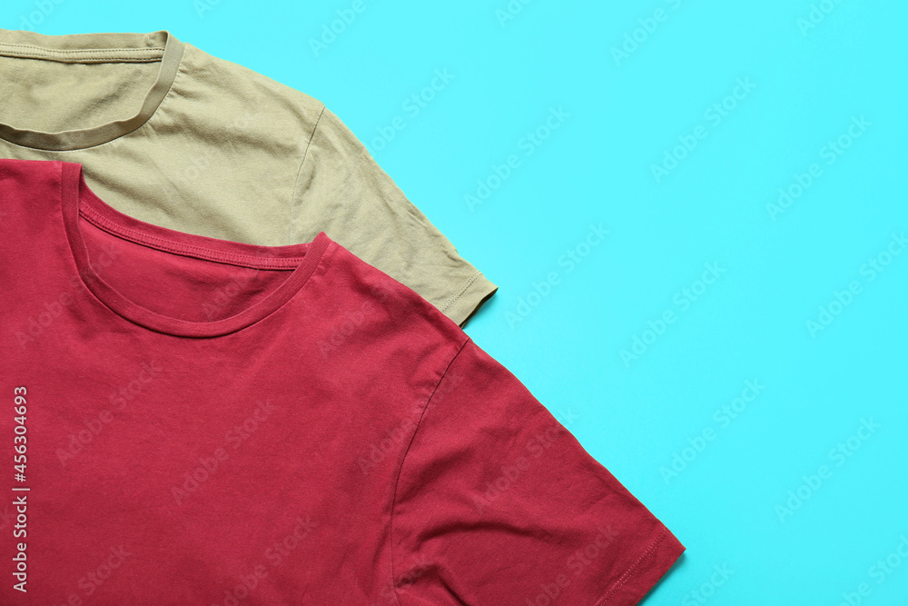 Stylish t-shirts on color background, closeup