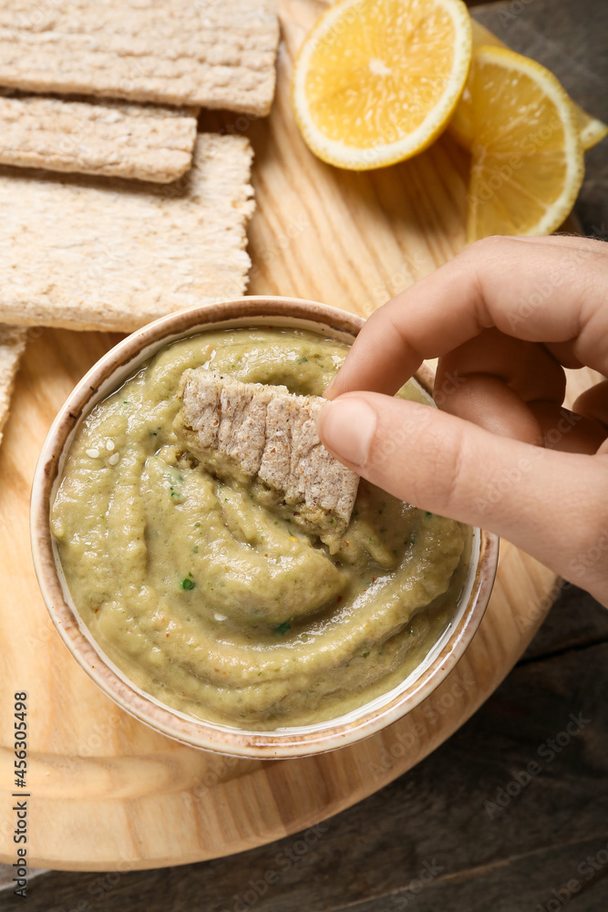 Man eating tasty baba ghanoush from bowl at table, closeup