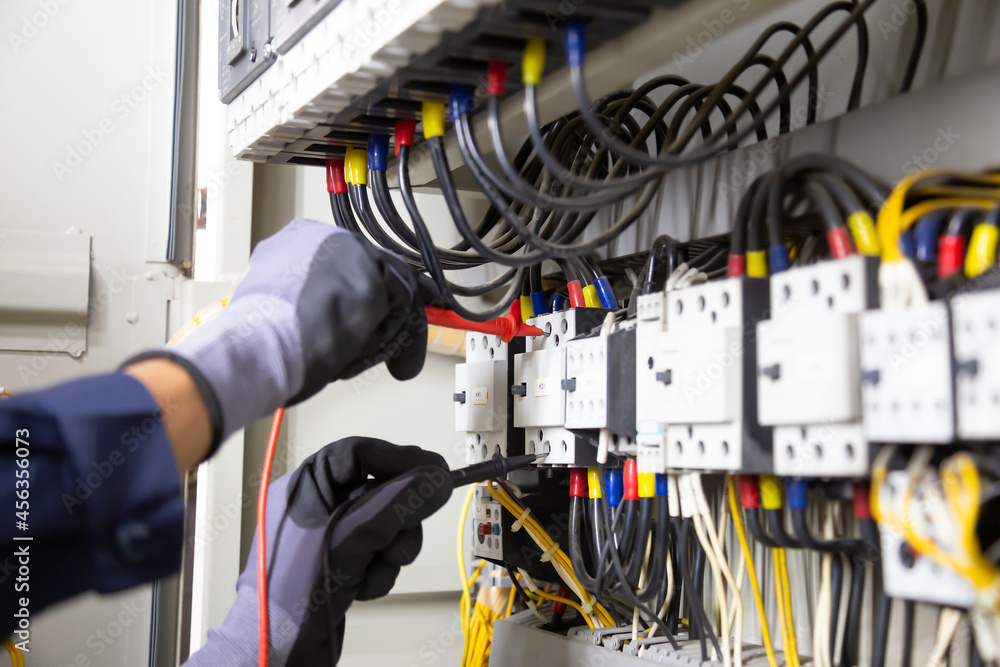 Electrician engineer tests electrical installations and wires on relay protection system. Adjustment