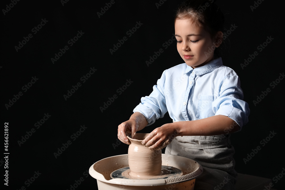 Little girl making ceramic pot on dark background