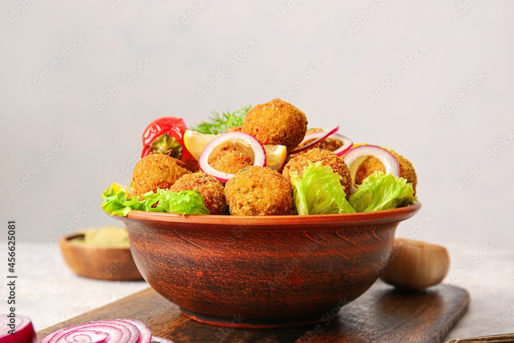 Bowl with tasty cod cutlets on table, closeup