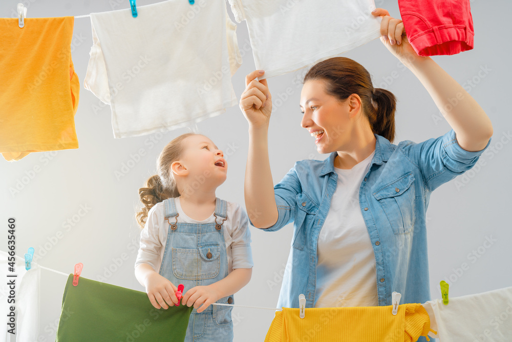 woman and girl hanging clothes on a rope