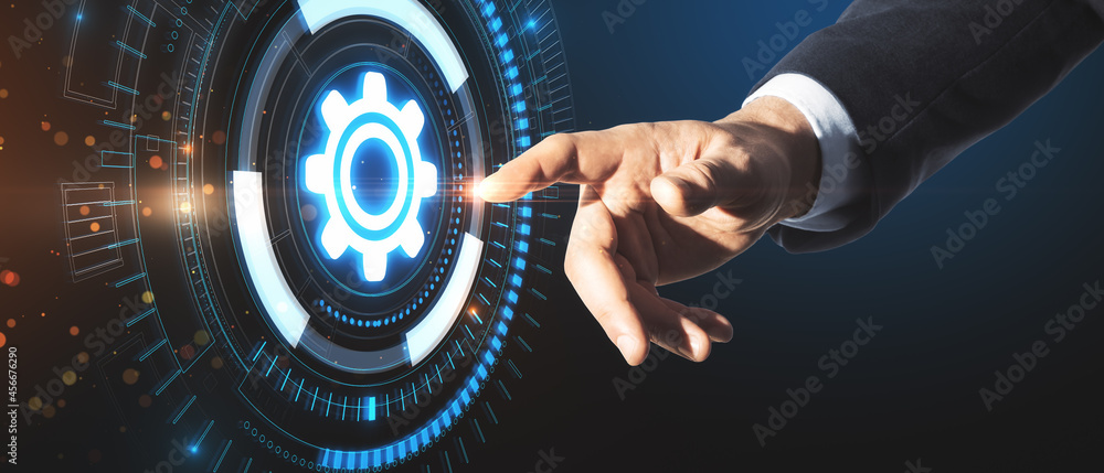 Close up of businessman hand pointing at creative glowing gears hologram on dark background. Busines