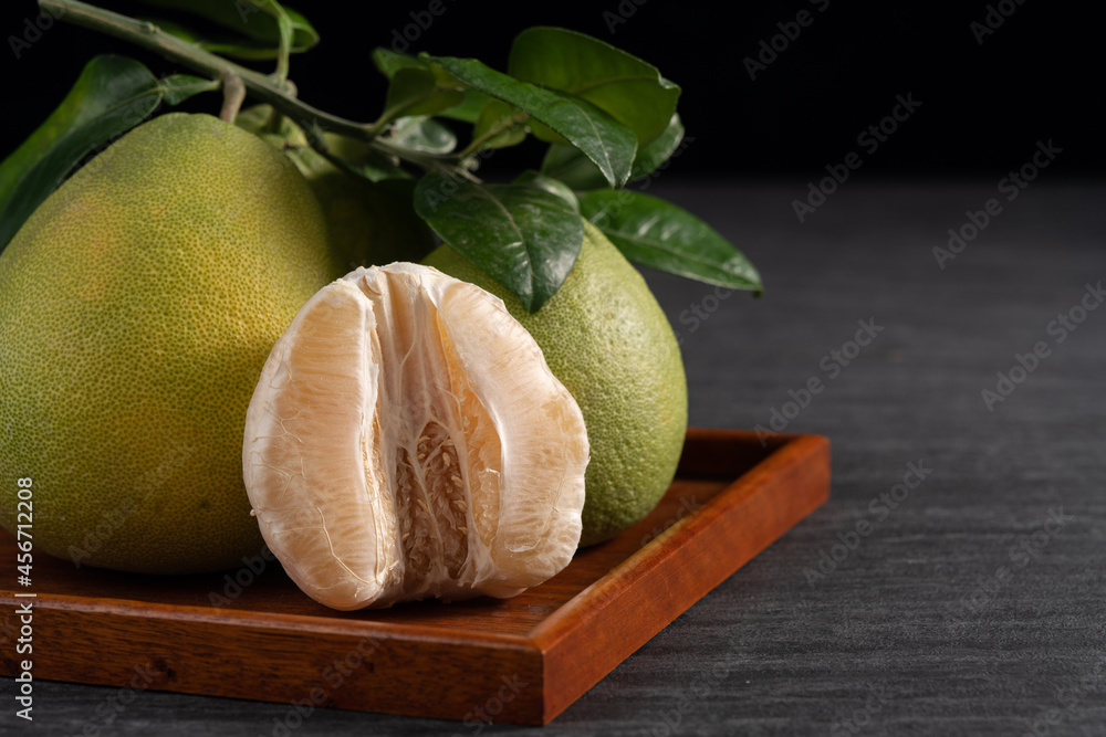 Fresh pomelo fruit on black slate background.