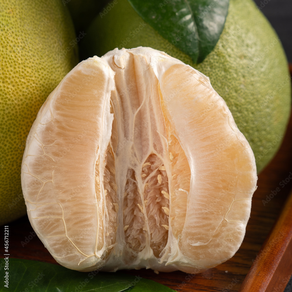 Fresh pomelo fruit on black slate background.