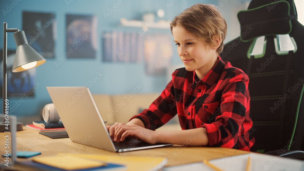 Smart Young Boy in Checkered Shirt Using Laptop Computer in Cozy Room at Home. Happy Teenager Browsi