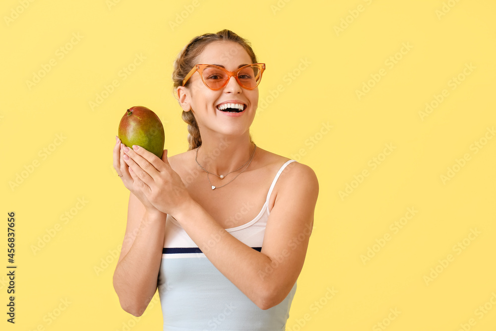 Beautiful woman with fresh mango on yellow background