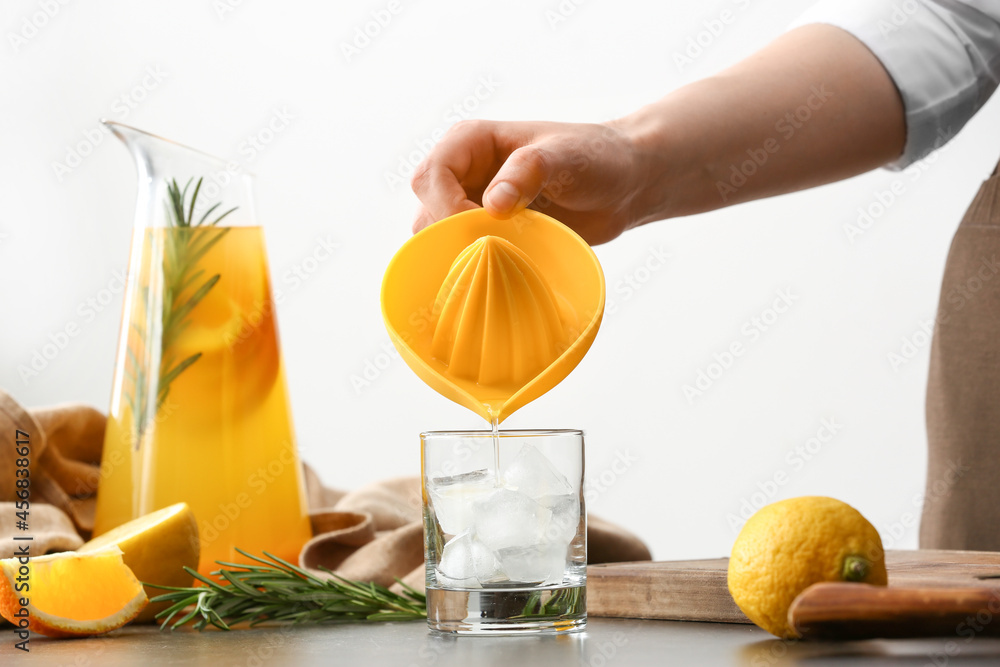 Woman pouring orange juice into glass on table in kitchen