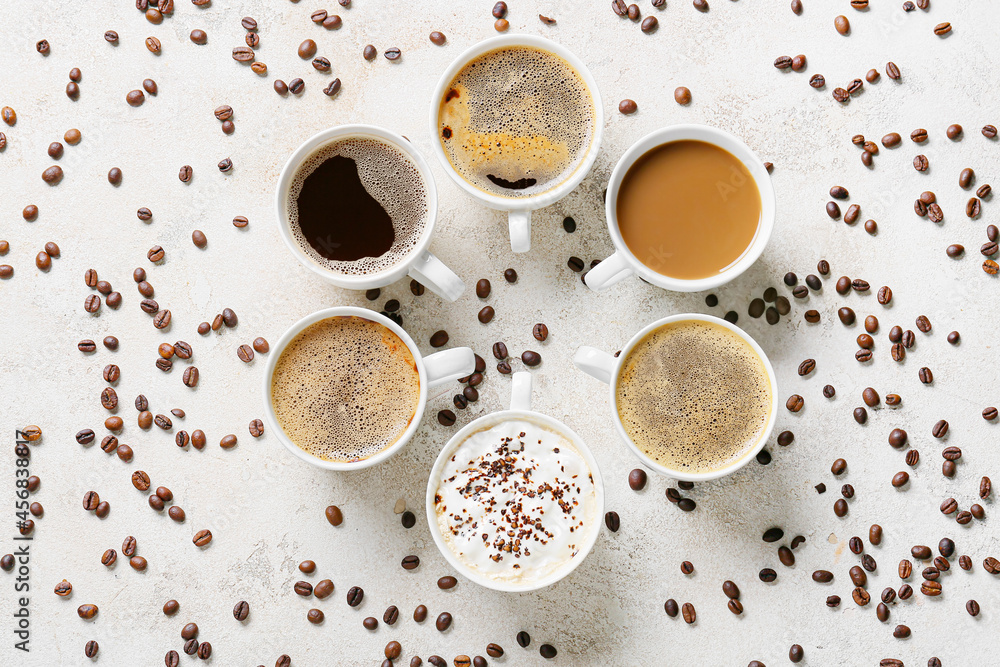 Cups of tasty coffee and beans on light background