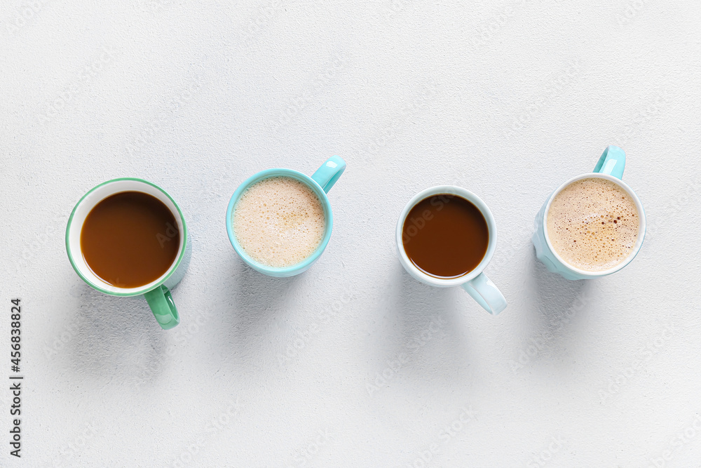 Cups of tasty coffee on light background