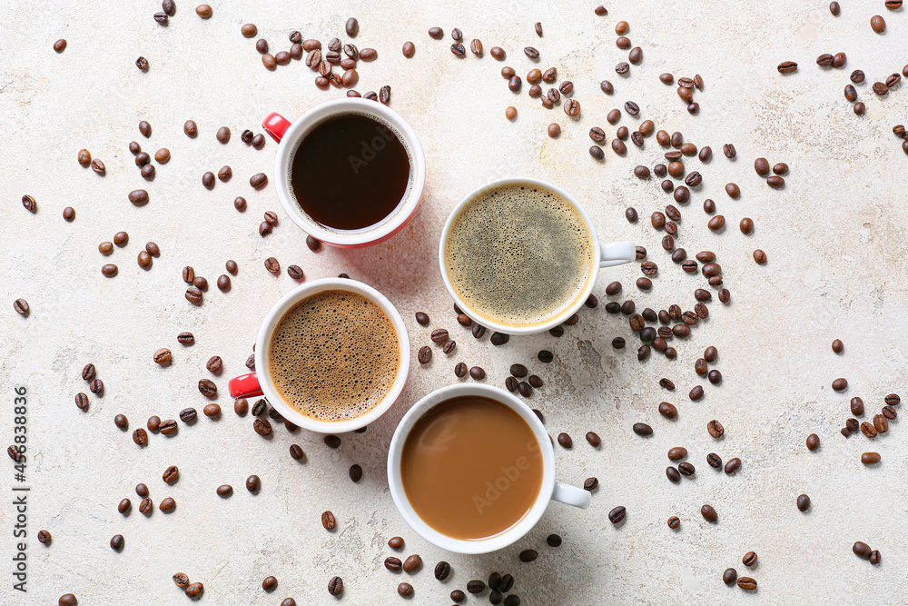 Cups of tasty coffee and beans on light background