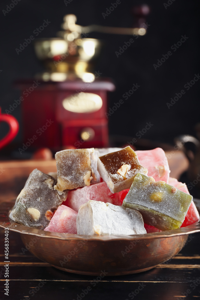 Plate with tasty Turkish delight on dark wooden background, closeup