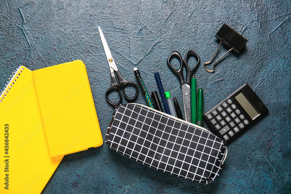 Stylish pencil case and stationery on dark background