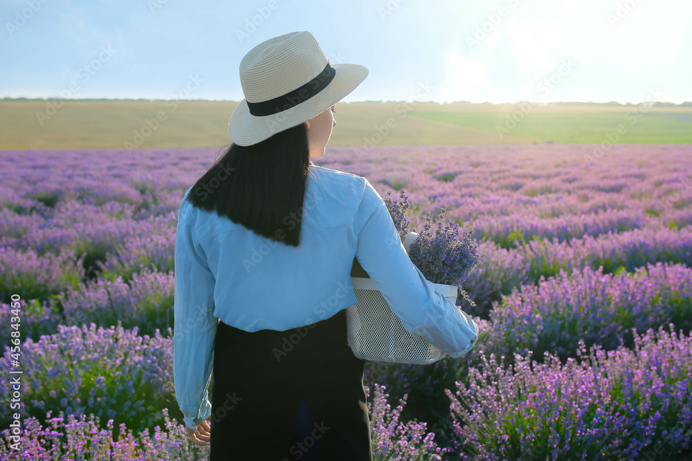 Female farmer holding basket with lavender flowers in field