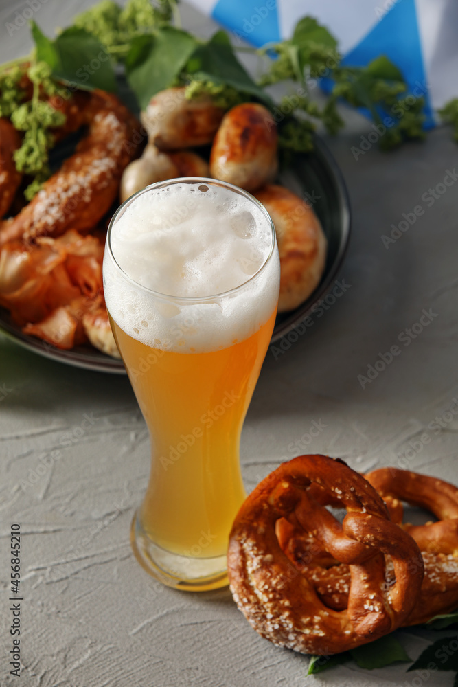 Glass of fresh beer and pretzels on grey background. Oktoberfest celebration