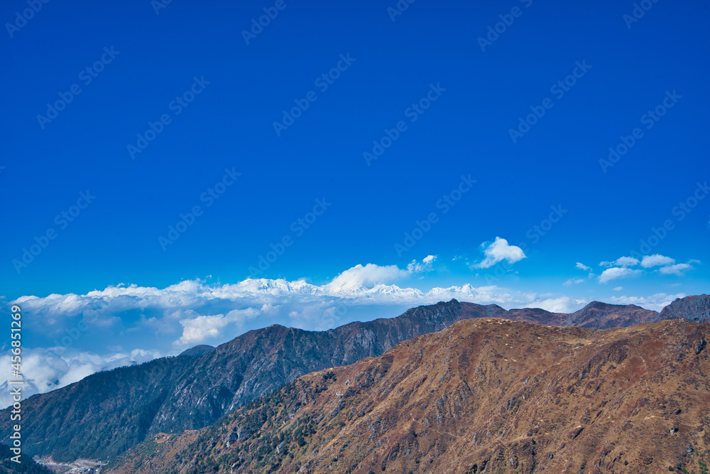 蓝天白云下茶色山脉的自然风光。山景