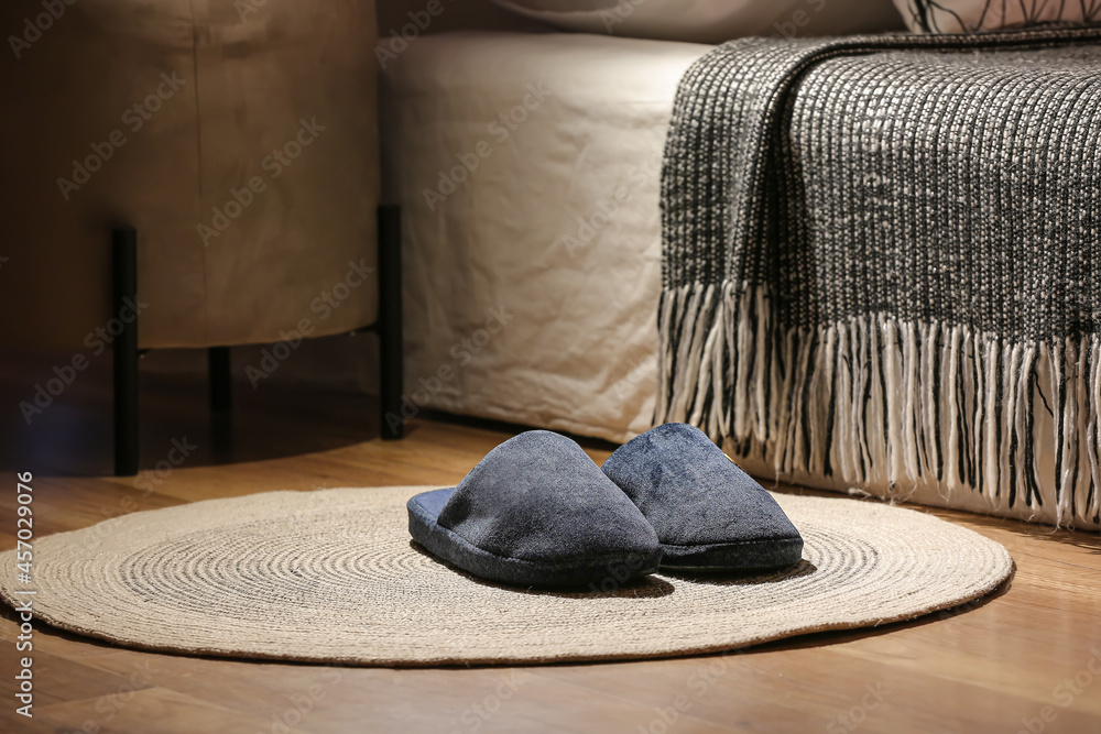 Male soft slippers on rug near bed