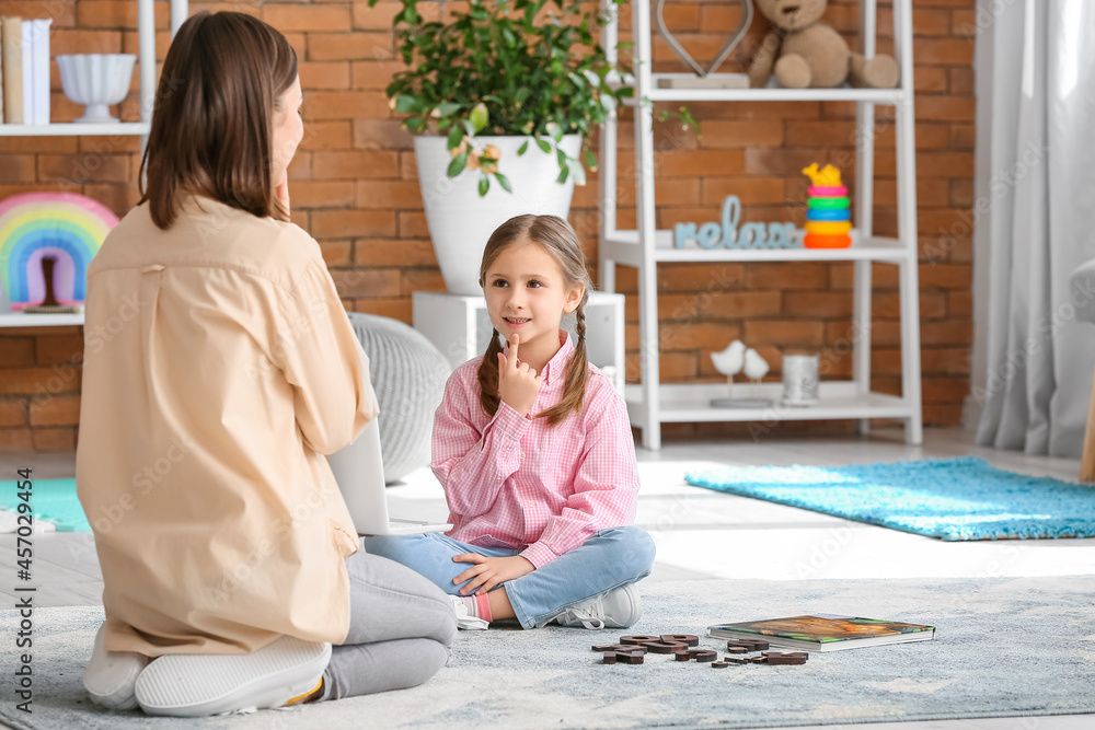 Speech therapist working with cute girl in clinic